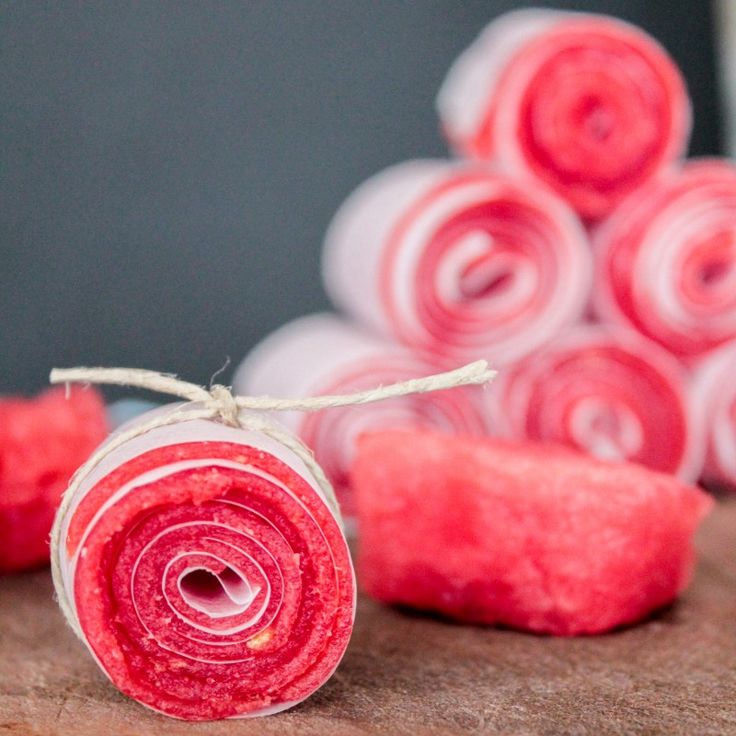 two rolls of red and white yarn on a table with some rolled up ones in the background