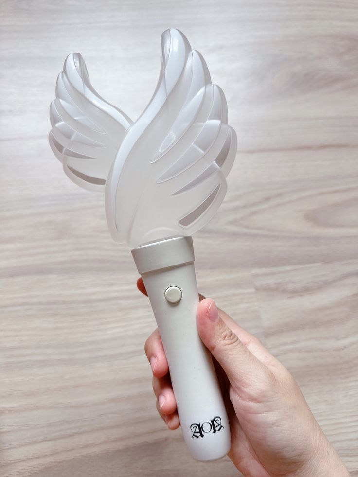 a hand holding a white hair dryer on top of a wooden table