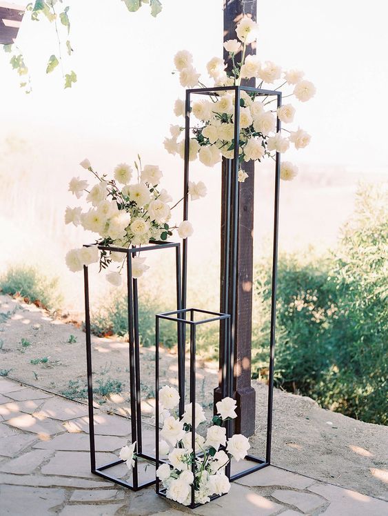 two tall vases filled with white flowers on top of a stone floor