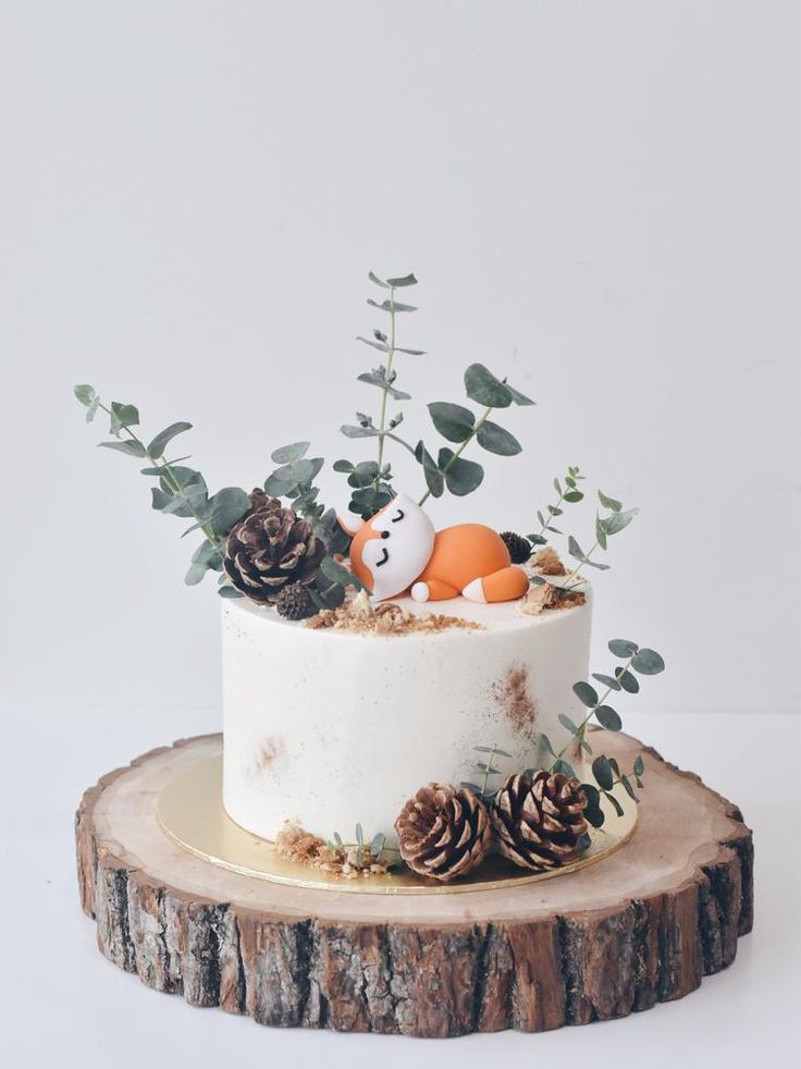 a cake decorated with pine cones, leaves and an animal figurine on top