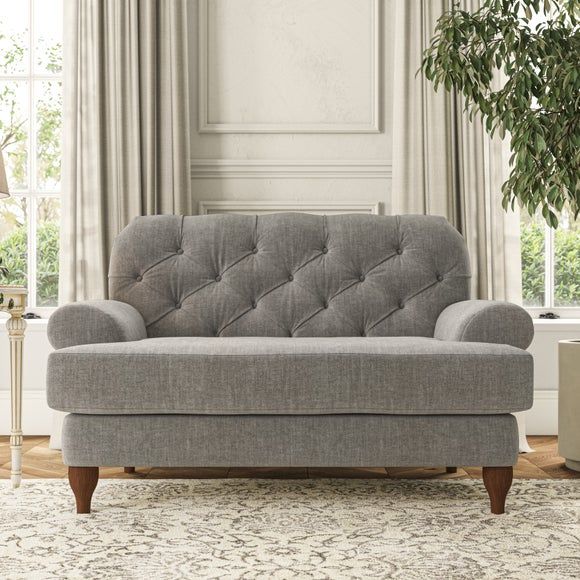 a gray couch sitting in front of a window next to a rug and table with a potted plant on it