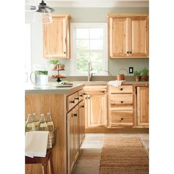 a kitchen with wooden cabinets and an area rug in front of the counter top that has wine bottles on it