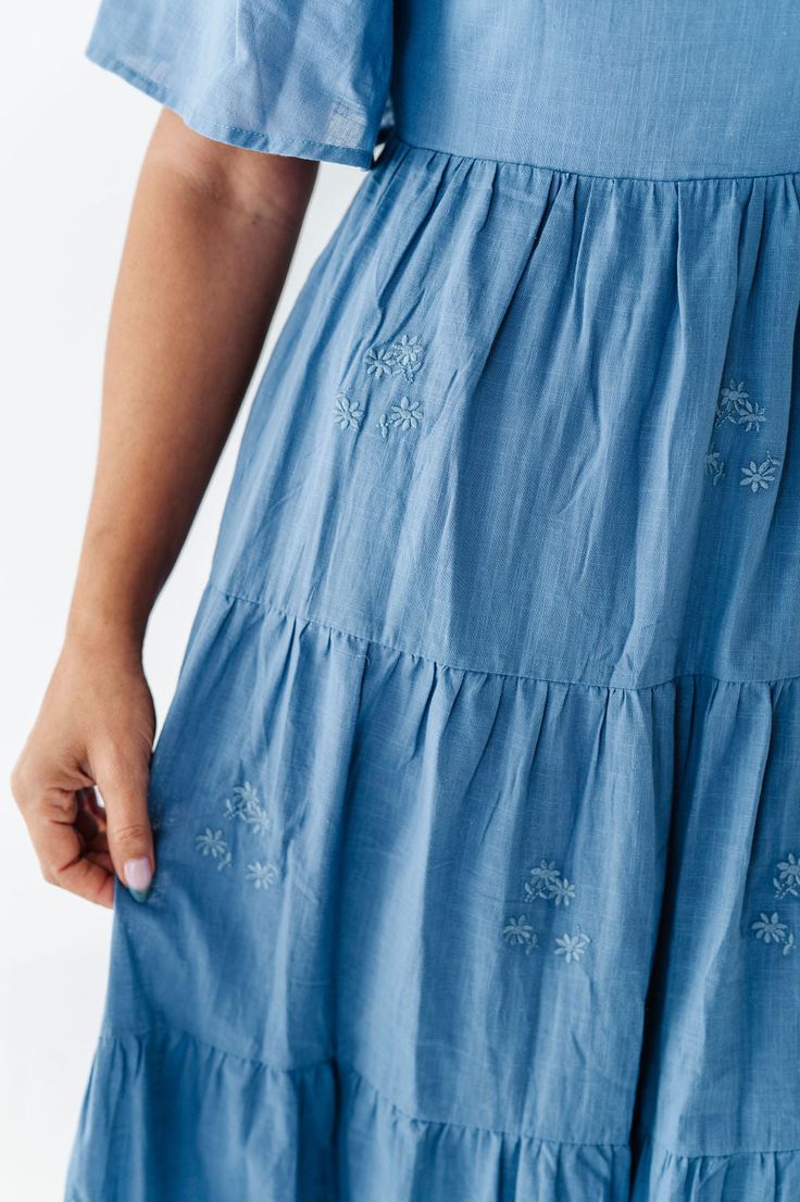 Features Sweetheart neck Flutter sleeves Tiered skirt with floral embroidered detail Smocked back Elastic waist Dusty blue color Pockets Self: 100% Cotton; Lining: 100% Polyester Size + Fit Small 0-4, Medium 4-8, Large 8-12, XL 14-18 Kristin is 5'4", a size 1 and is wearing a Small Runs true to size. Measurements taken while laying flat and then doubled. They do no account for stretch. Click here for shoes Size Bra Band Length Small 34" 49" Medium 36" 49" Large 38" 50" X-Large 40" 50" Light Blue Tiered Skirt Dress, Flowy Tiered Skirt Dress With Floral Embroidery, Tiered Dress With Floral Embroidery, Summer Floral Embroidered Tiered Skirt Dress, Summer Floral Embroidered Tiered Dress, Light Blue Tiered Skirt Summer Dress, Light Blue Tiered Skirt Dress For Spring, Blue Tiered Skirt Dress With Elastic Waistband, Light Blue Tiered Skirt Dress For Summer