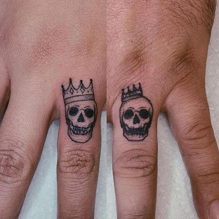 two fingers with skulls and crowns tattooed on them