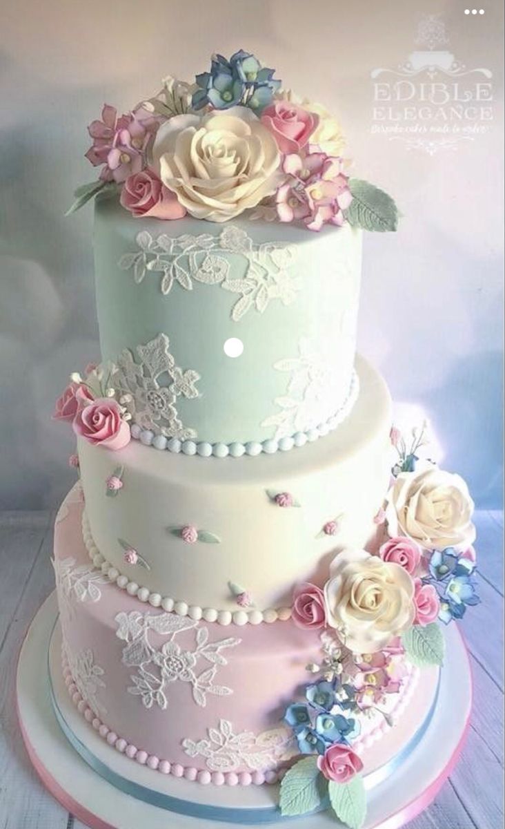 a three tiered cake with flowers and pearls on the top is decorated in pastel colors