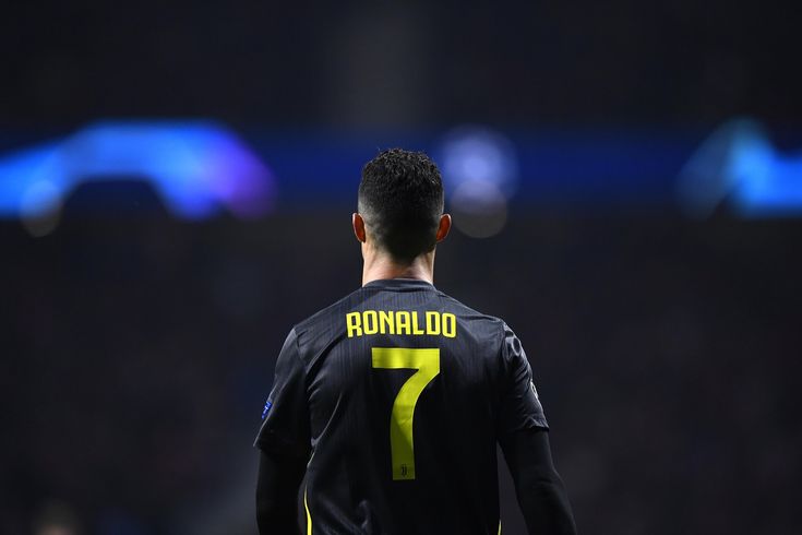 a soccer player in black and yellow uniform standing on the field with his back turned to the camera