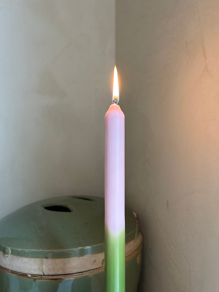 a lit candle sitting on top of a trash can next to a green trash can