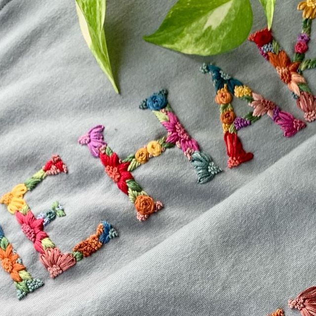 the word faith is made out of crocheted letters and flowers on a gray blanket