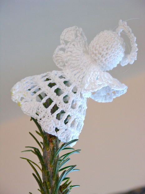 a crocheted angel decoration sitting on top of a green plant in a vase