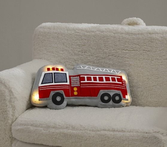 a red fire truck shaped pillow sitting on top of a white chair