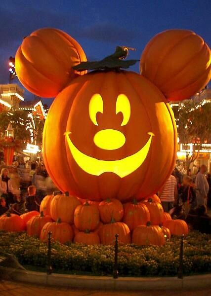 a mickey mouse pumpkin is lit up at night