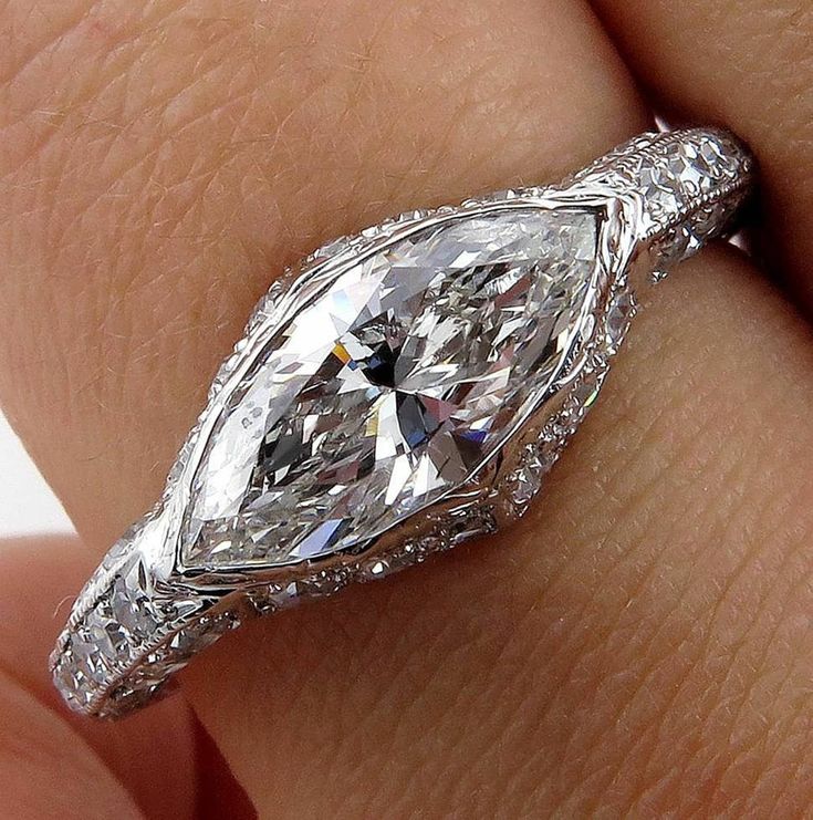 a woman's hand holding an engagement ring with a pear shaped diamond in the center