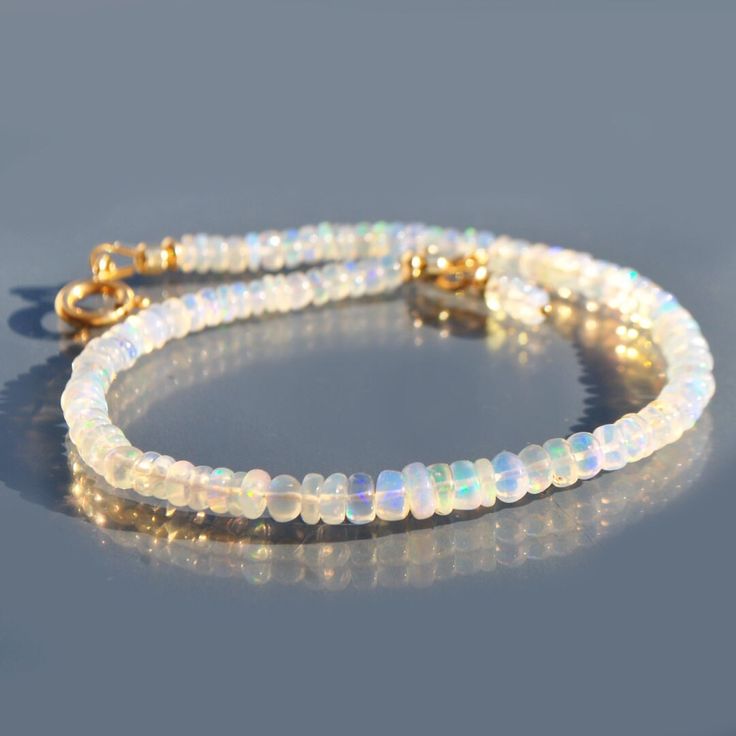 Opal Welo 14K Gold Bracelet, designer jewelry Christin Piedra, Toulouse. Subtle elegance for this bracelet, with its striking iridescent shine, it evokes purity and spiritual openness. A touch of sophistication is added by the small pendant attached to the clasp ring. Each stone, carefully selected for its exceptional quality and unique vibration, gives this jewel a deep meaning. The whole transcends appearance, establishing a spiritual connection. The ring-shaped clasp and all 14K Gold Filled f Iridescent Bangle Jewelry For Gifts, Elegant Iridescent Bracelet Jewelry, Flexible White Jewelry For Anniversary, White Faceted Bracelet Jewelry, Gold Armband, Subtle Elegance, Deep Meaning, Opal Bracelet, Spiritual Connection