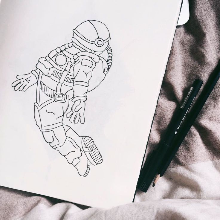 a drawing of an astronaut floating in space on top of a sheet of paper next to a pen