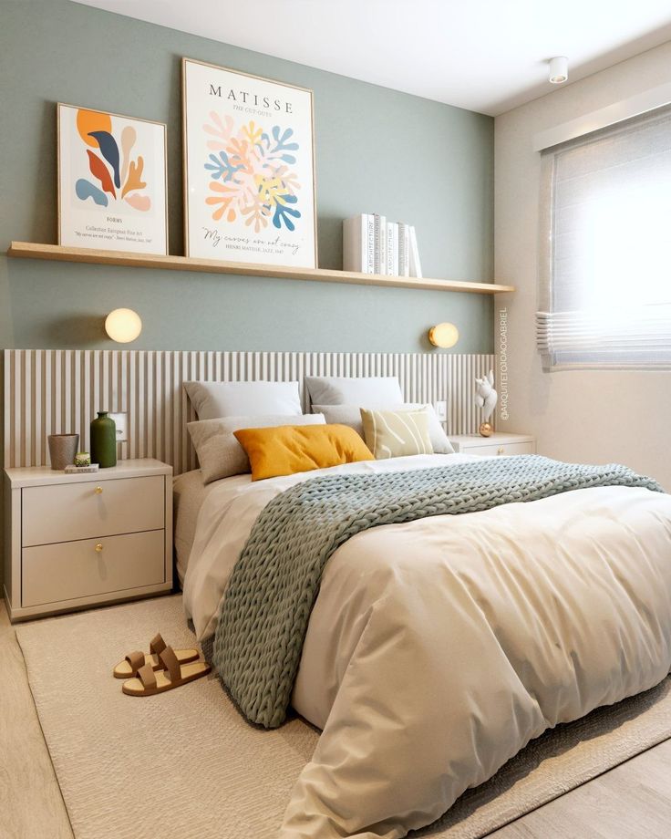 a bed sitting in a bedroom next to a window with two pictures on the wall