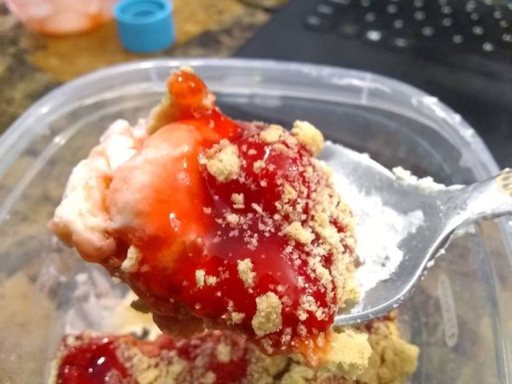 a spoonful of strawberry shortcake with powdered sugar on top in a plastic container