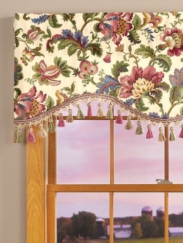 a window with a flowered valance and tassels hanging from it's side