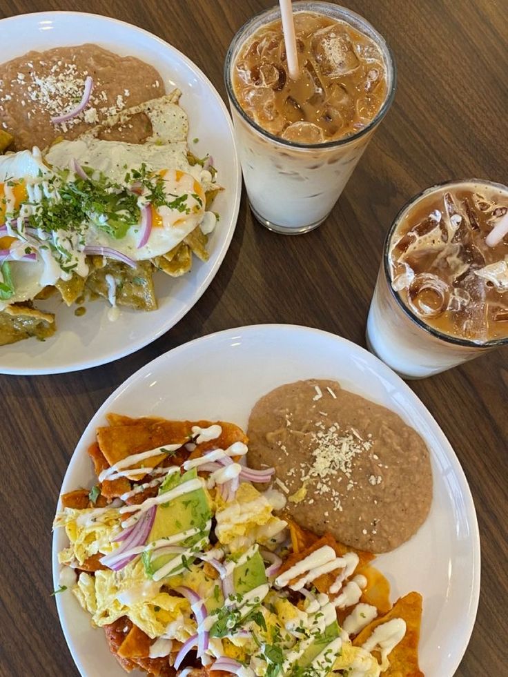 two white plates topped with different types of food next to cups filled with drinks and ice cream