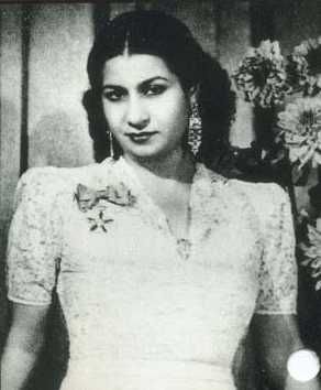 an old black and white photo of a woman wearing a dress with flowers on it