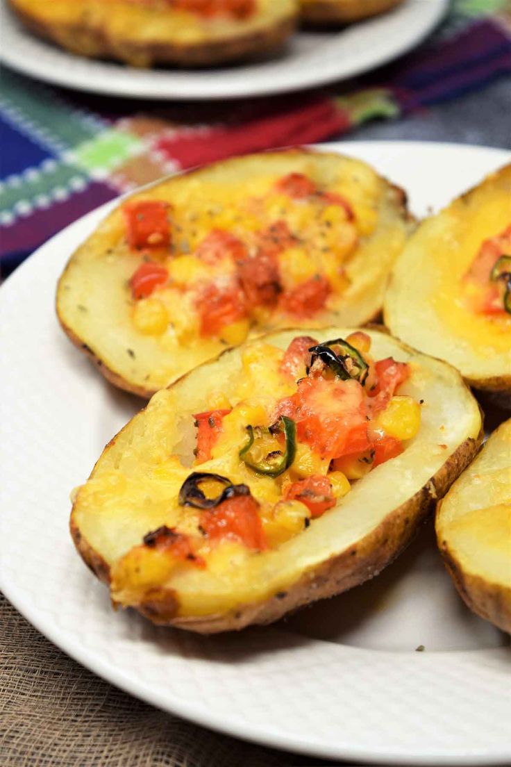 baked potatoes with tomatoes and cheese are on a white plate, ready to be eaten