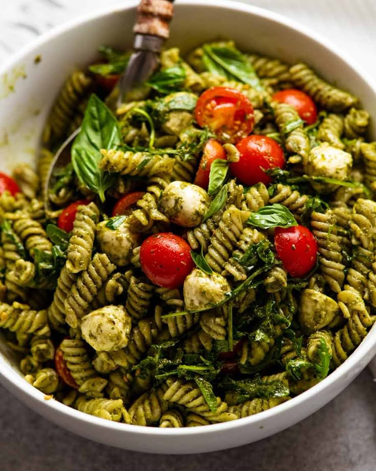 a bowl filled with pesto pasta and cherry tomatoes