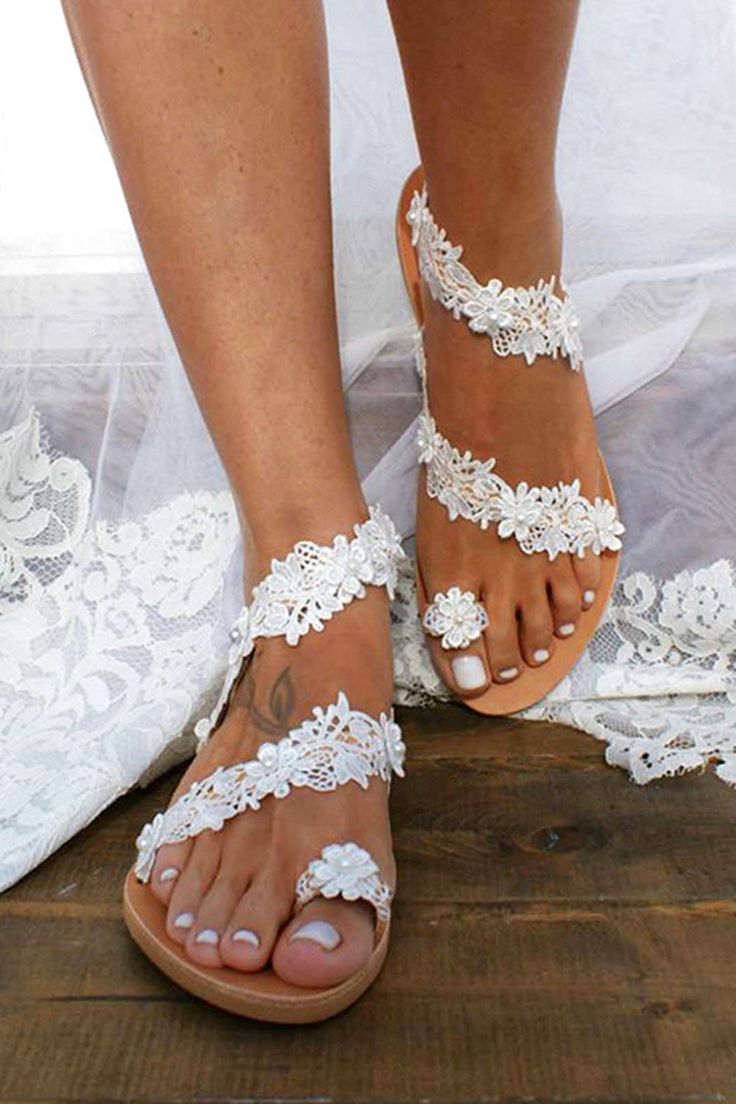 a bride's feet with white lace and flowers on the toes, wearing sandals