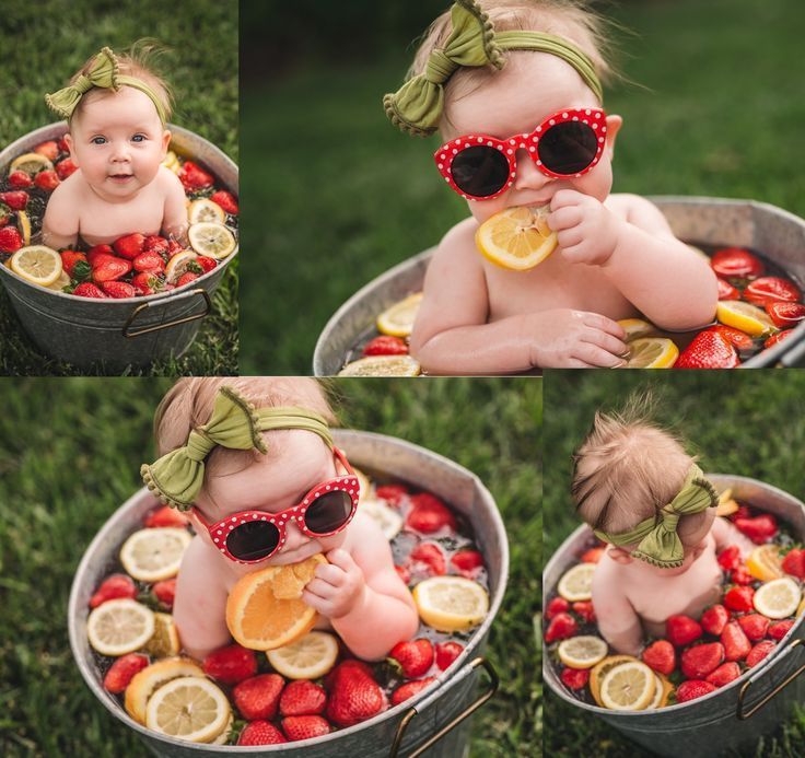 a baby wearing sunglasses and sitting in a tub filled with strawberries and lemons