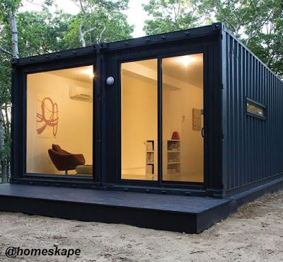 a small house made out of shipping containers in the woods with its doors open to let in natural light