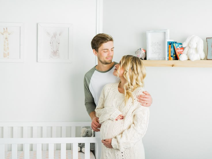 a man and woman standing next to each other near a baby crib in their nursery