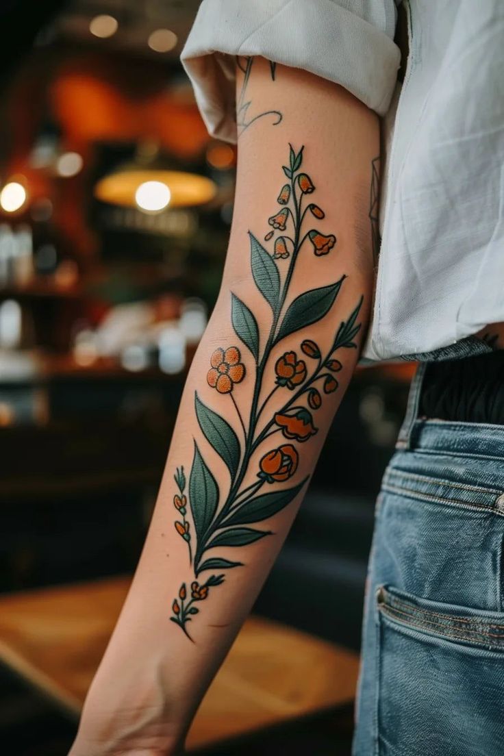 a woman's arm with flowers and leaves tattooed on the left side of her arm