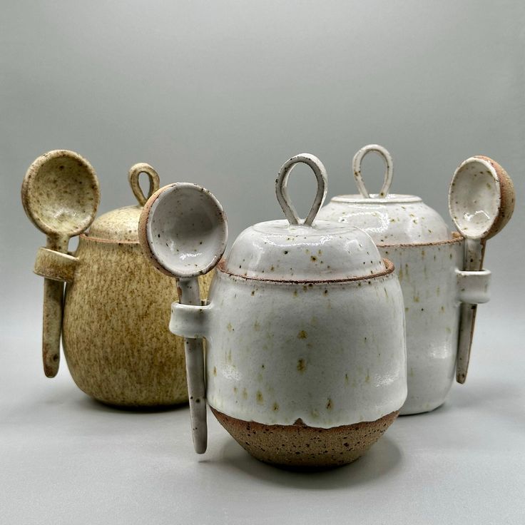 three ceramic pots and spoons with handles