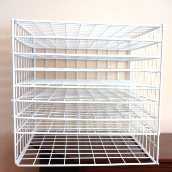 a white wire shelf sitting on top of a wooden table