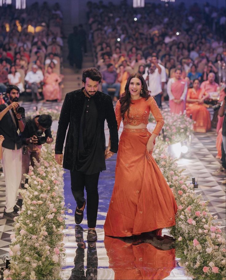 a man and woman walking down a runway