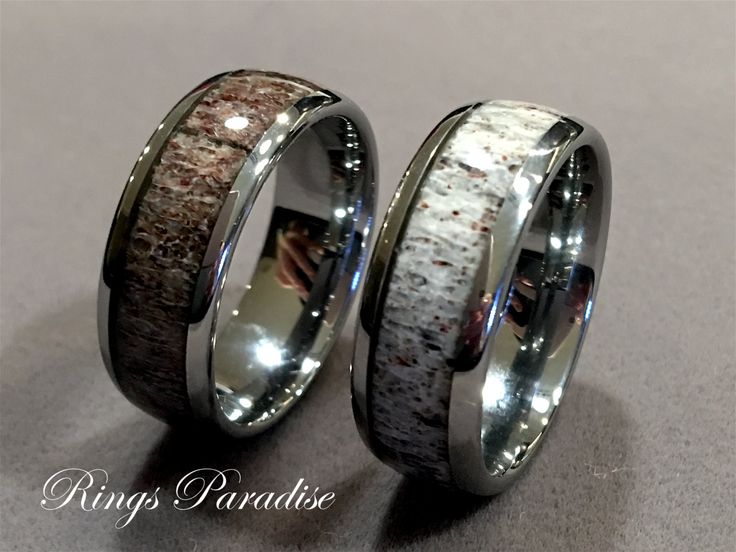 two wedding rings with antler wood inlays on each side, one is black and the other is white