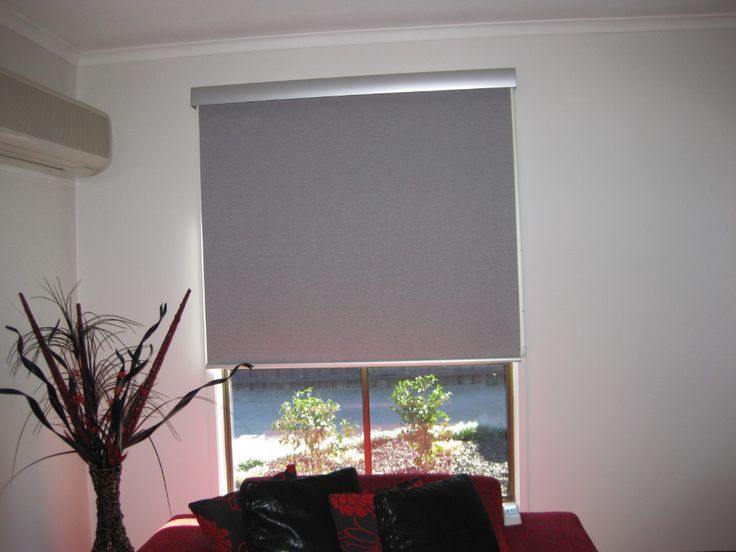 a red couch sitting in front of a window with a blind on top of it