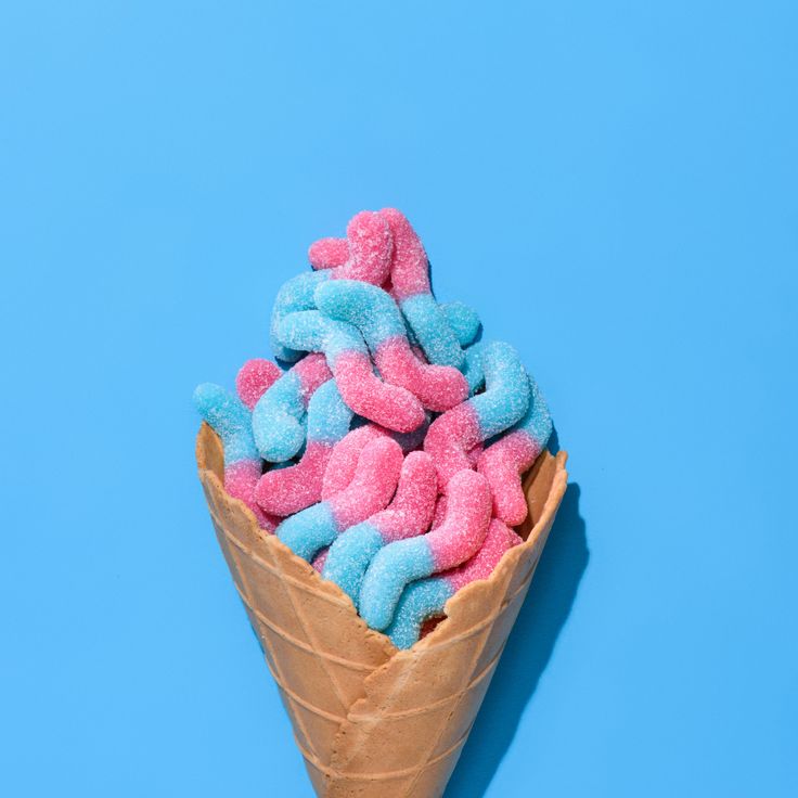 a cone filled with pink and blue sprinkles on top of a blue background