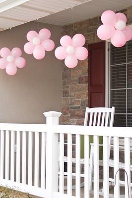 some pink balloons are hanging from a porch