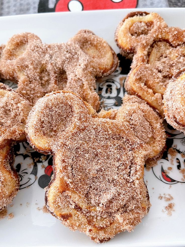 some sugared pastries are on a plate with mickey mouse stickers in the background