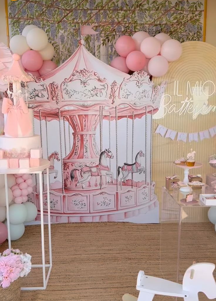 a pink and white carousel themed birthday party with balloons, cake stands, and decorations