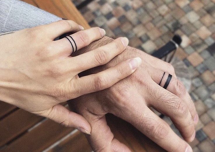 two people holding hands with wedding rings on their fingers and the other hand is touching each other