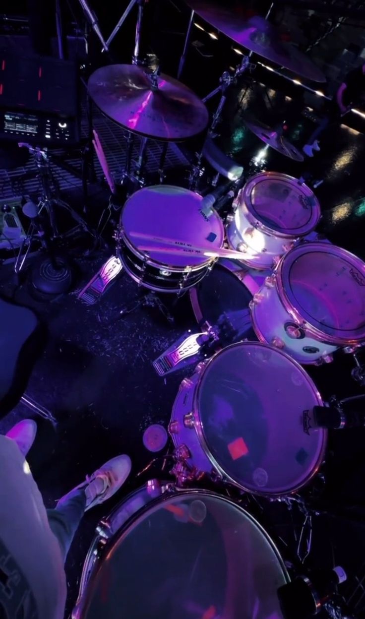 a drum set up with purple lights in the background