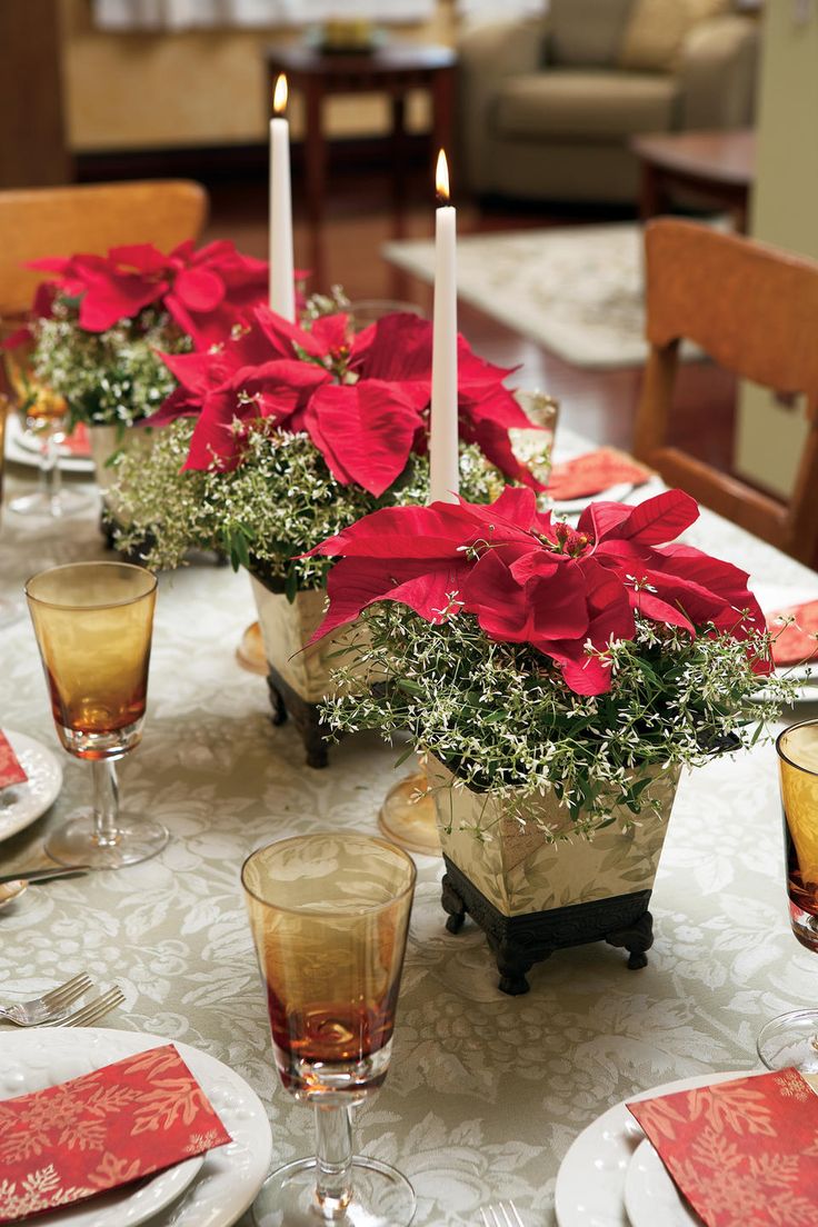 the table is set with candles and poinsettis in vases on it