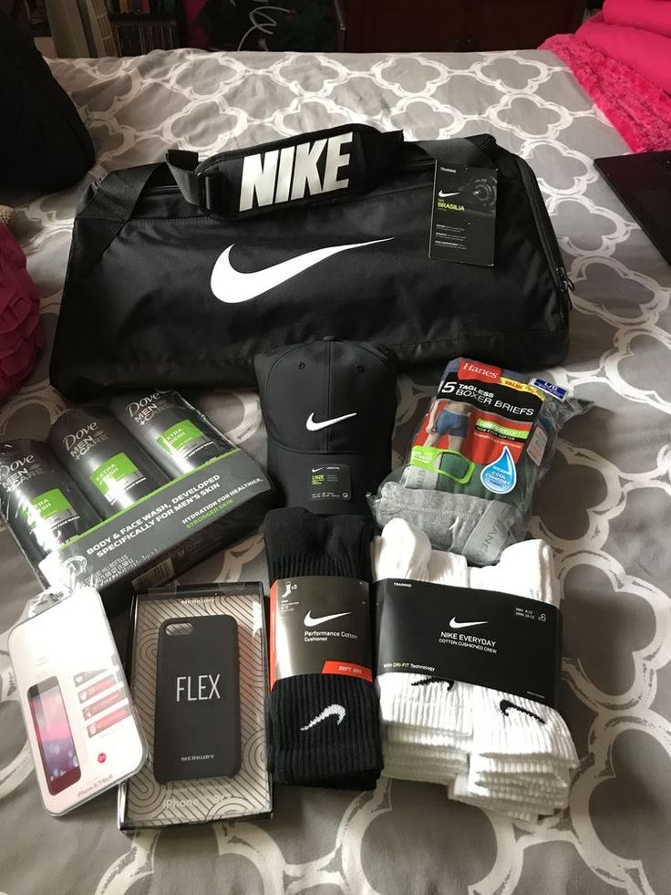 the contents of a nike duffle bag laid out on a bed with other items