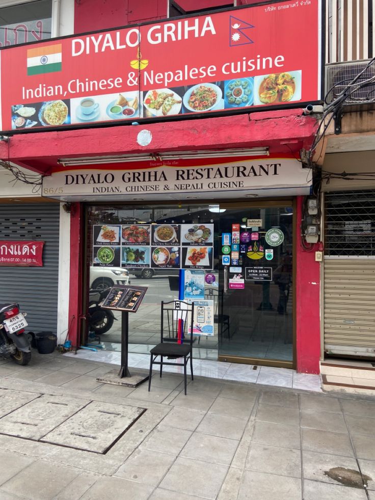 the front of a chinese restaurant with signage on it's side door and chairs outside