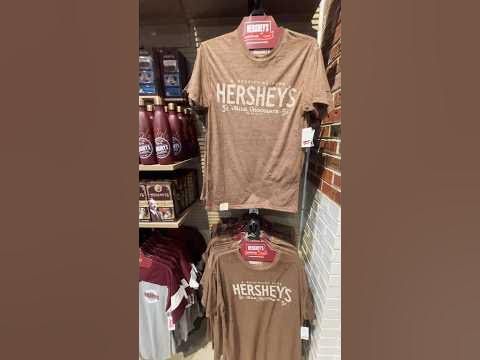 two t - shirts are on display in a store, one is brown and the other is red