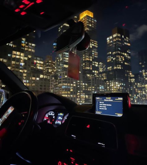 the interior of a car with city lights in the background