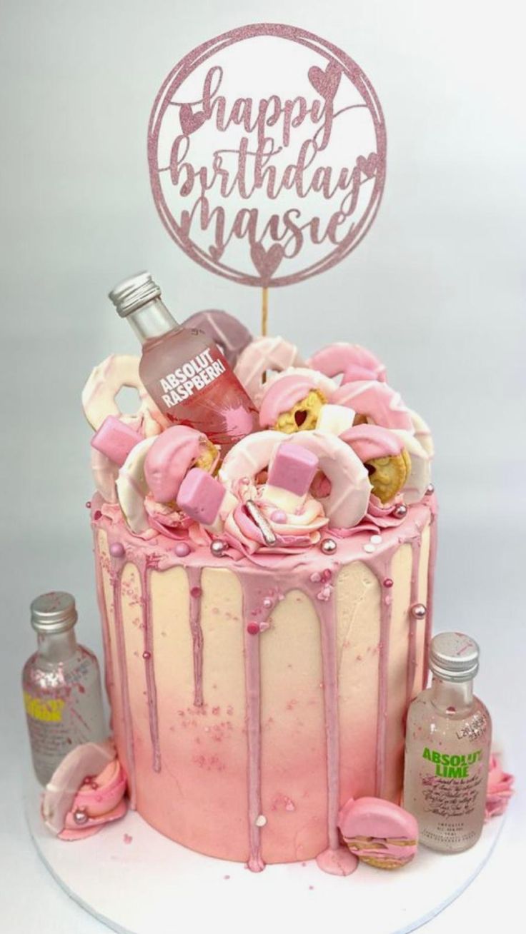 a birthday cake decorated with pink icing and frosting, including a bottle of booze