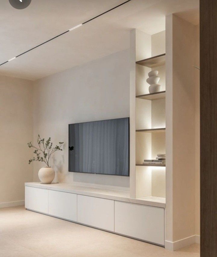 an empty living room with a large flat screen tv on the wall and shelves in front of it