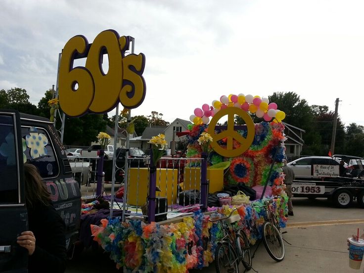 a woman standing in front of a float with balloons and peace signs on it's side