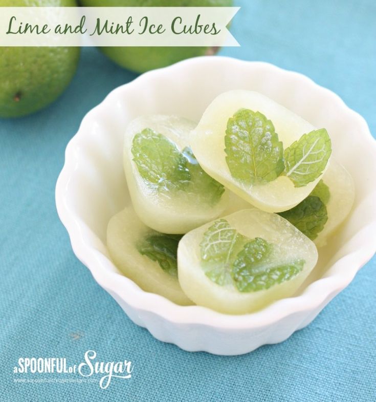 lime and mint ice cubes in a white bowl on a blue tablecloth next to green apples